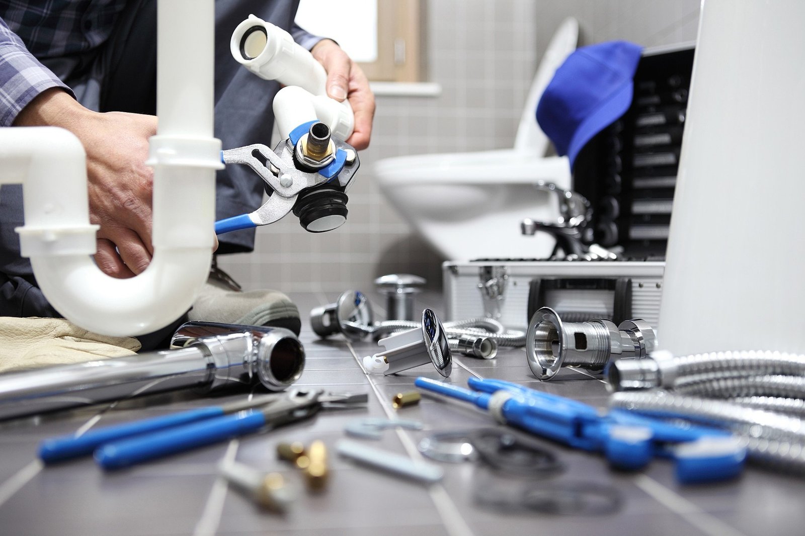 Profissional realizando manutenção hidráulica com ferramentas e conexões